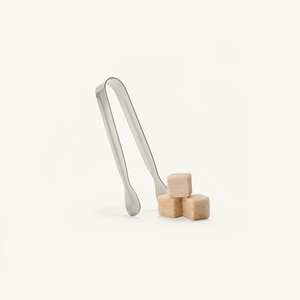 Metal tongs with sugar cubes on a white background