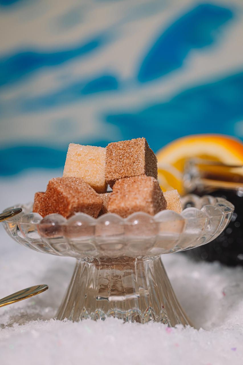 Brown LUXE Mixer Cubes on a decorative glass plate with a blurred colorful winter background