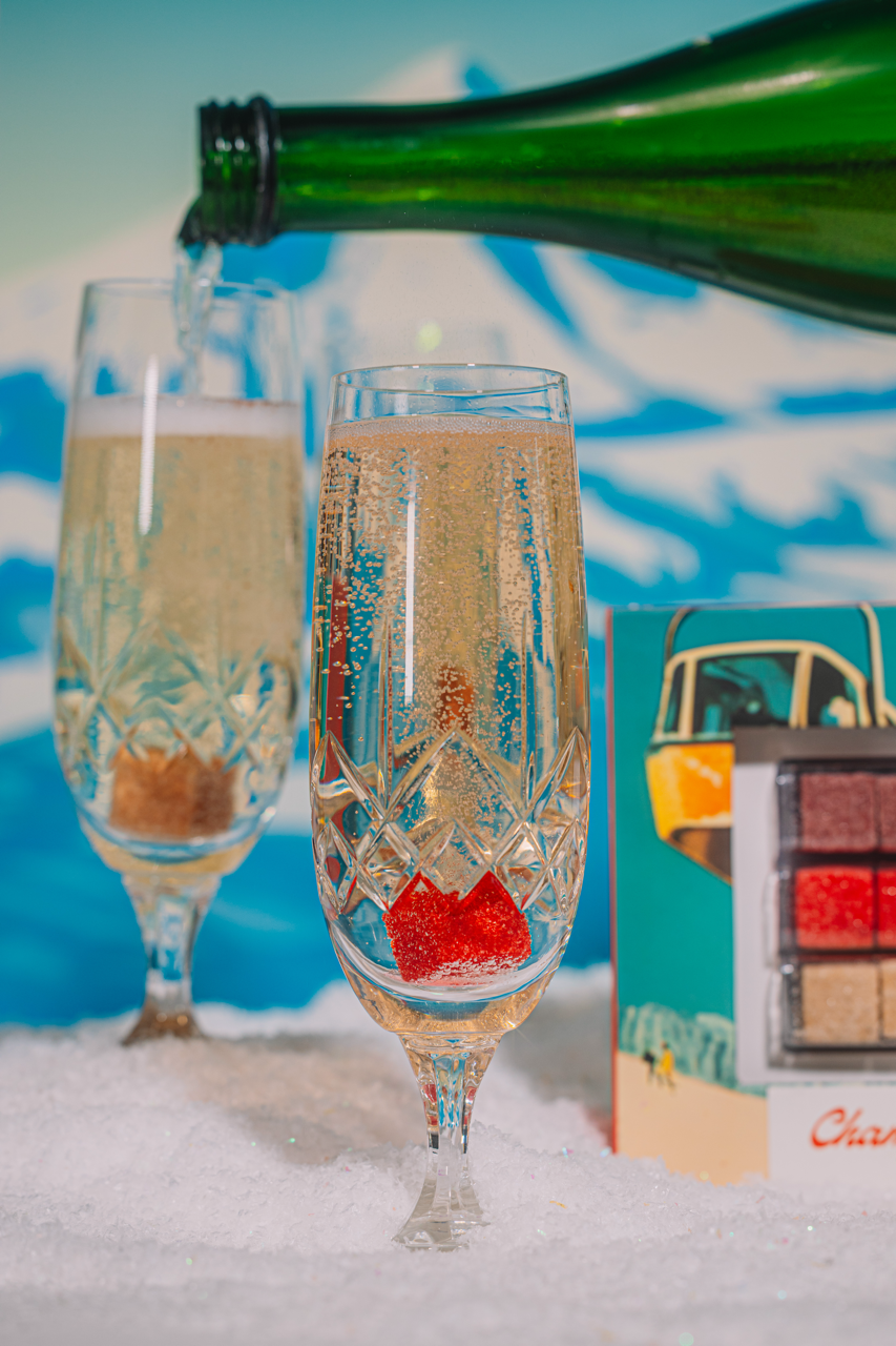 Champagne being poured into two glasses with a scenic background
