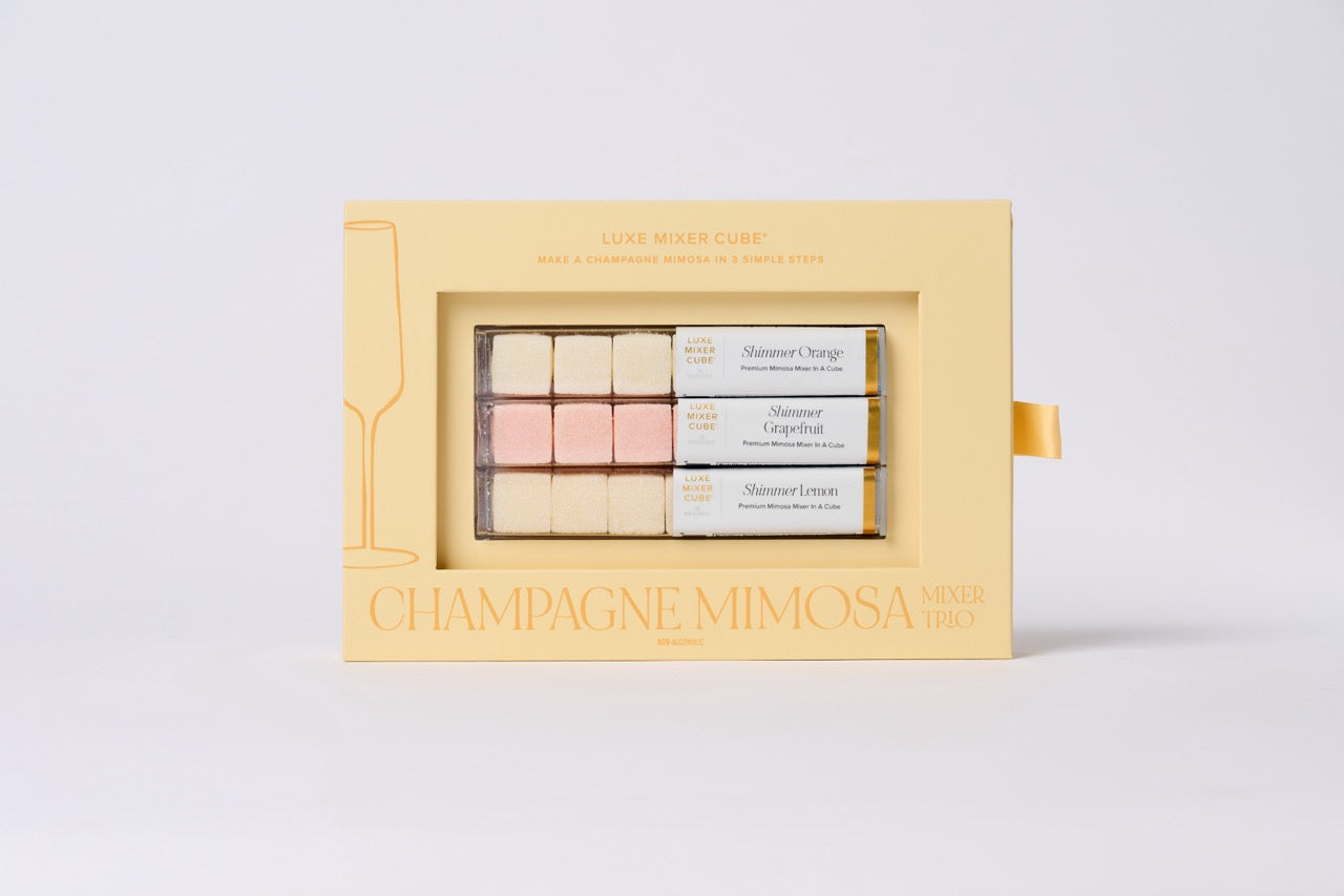 Set of champagne mimosa makeup products in a decorative box on a light gray background