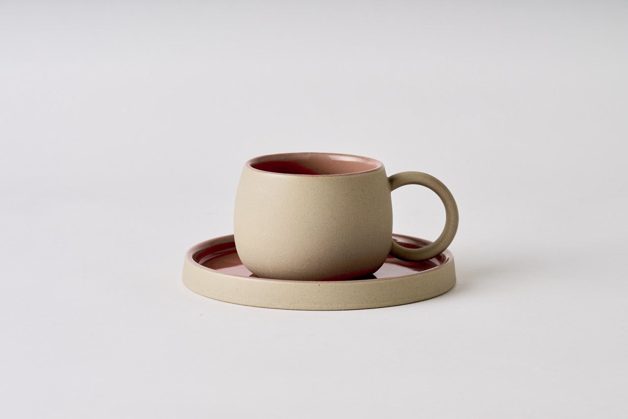 Ceramic mug and coaster set on a light gray background