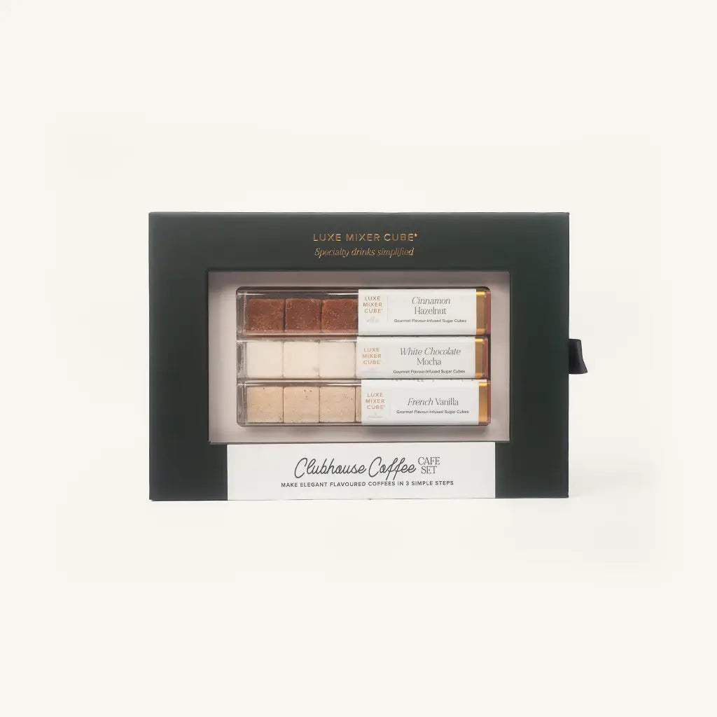 A Luxe Mixer Club by Claiborne Coffee Cafe Set in a black presentation box with a clear window showing three small coffee-flavored stick packs: Cinnamon Madness, White Chocolate Mocha, and French Vanilla.
