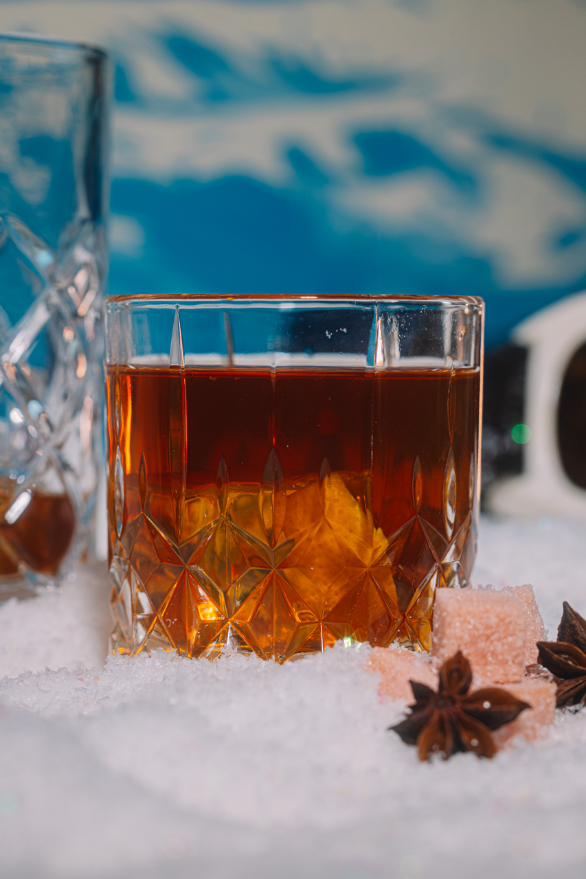 Glass of amber bourbon with decorative elements on a snowy surface