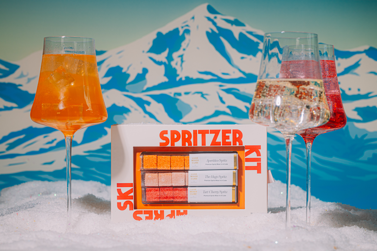 Spritzer kit with glasses of orange and red drinks against a mountainous background