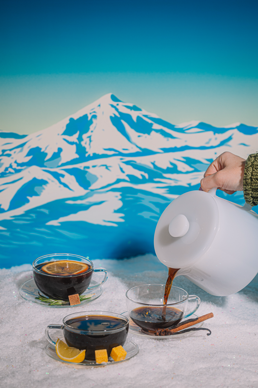 Person pouring coffee into cups with a snowy mountain in the background