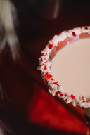 Close-up of a cocktail with a red and white rim on a dark background
