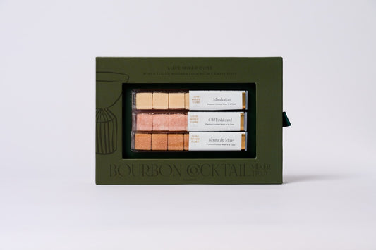 Set of bourbon cocktail mixers in a green box on a light gray background
