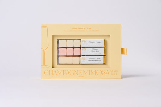 Set of champagne mimosa makeup products in a decorative box on a light gray background