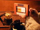 A hand holds a boxed artisanal coffee gift set labeled 'Pecan Pie latte Mixer trio' against a warm, dimly lit brown background with a plate of pecan pie and a glass bowl or sugar cubes nearby.