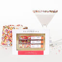A product image featuring a 'Birthday Party Kit' by TEASPRESSA, which includes various flavored drink cubes and birthday-themed garnishes, displayed alongside a glass of milk with sprinkles on the rim.